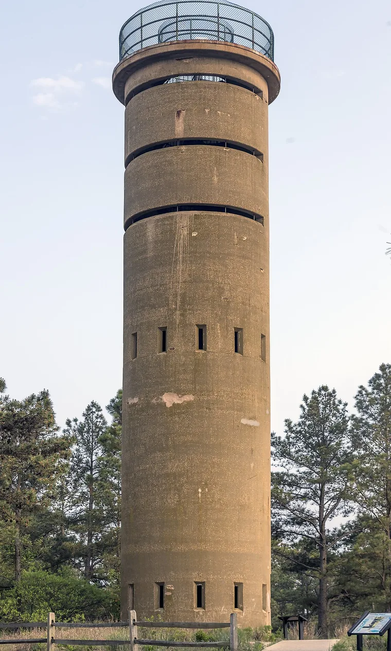 Fire Control Tower 7 at Cape Henlopen State Park, a tall concrete cylinder with narrow observation slits and a glassed-in gallery added at the top.